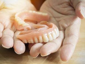 Close up of female hands holding flexible nylon denture.