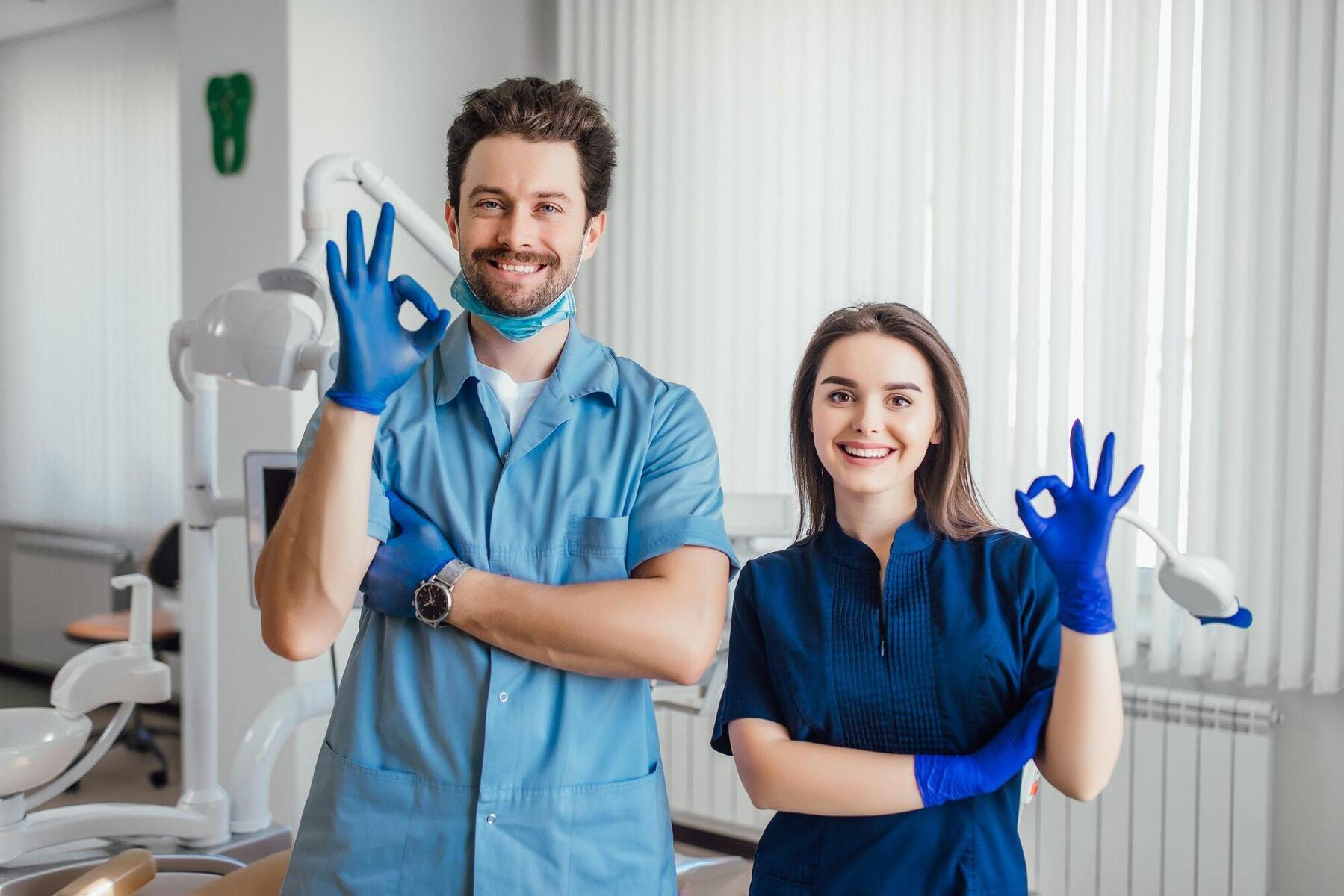 photo-smiling-dentist-standing-with-arms-crossed-with-her-colleague-showing-okay-sign-scaled.jpg