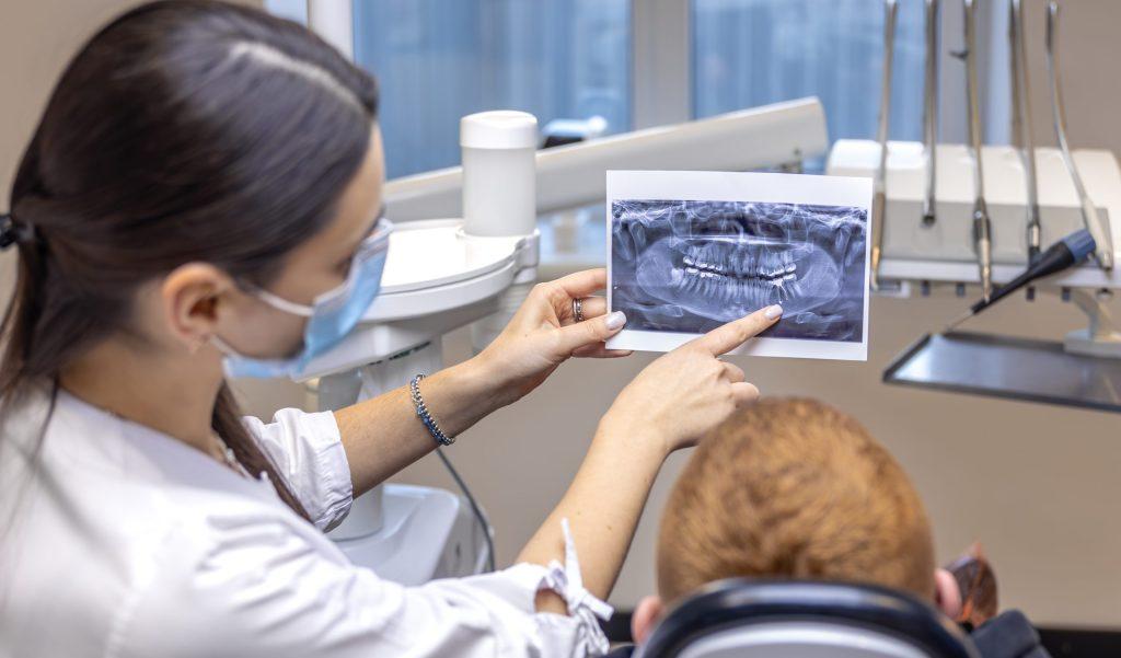 Young female dentist showing a patient a dental x-ray. Dentistry concept.